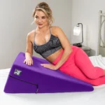 Beautiful woman in pink tights and black sports bra resting on the purple Liberator Ramp Sex Pillow | Regular size 12"x24"x34"