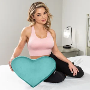 Beautiful woman sitting in bed with the blue Liberator Heart Wedge Sex Pillow