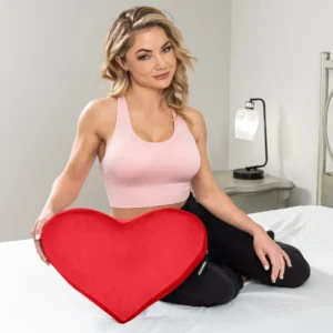 Beautiful woman sitting in bed with the red Liberator Heart Wedge Sex Pillow