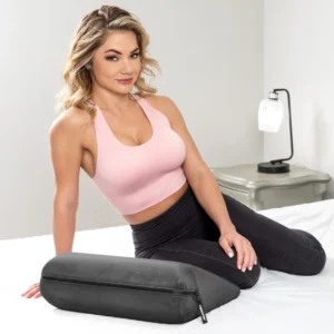 Beautiful woman in pink sports bra and black tights sitting in bed next to the Liberator JAZ Original Sex Pillow - Black